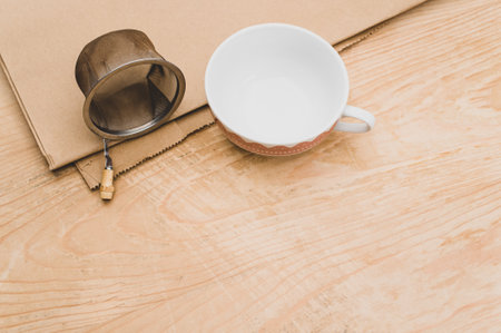 metal tea strainer and decorated tea cup on a kraft paper and wooden background with text spaceの写真素材