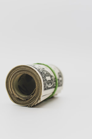 US dollar banknotes rolled up on a white tabletop with text spaceの写真素材