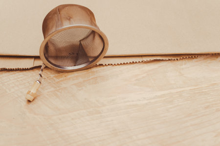 metal tea strainer on a kraft paper and wooden background with text space