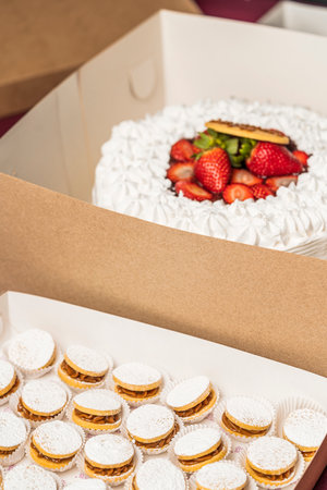 Vertical photo of boxes with cakes of candy and strawberry with cream ready to sell in a bakeryの写真素材