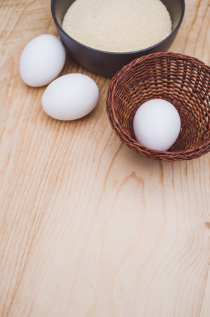 white eggs and dark gray bowl with wholegrain flour on worn wooden background with copy spaceの写真素材