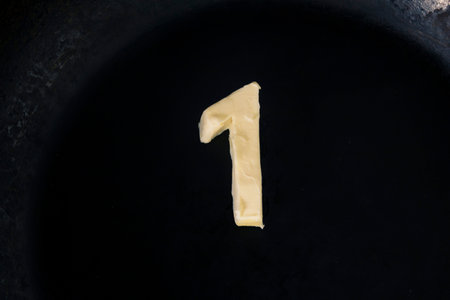 Butter in shape of number 1 on hot pan - Close up top view.の写真素材