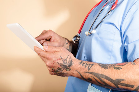 Cropped shot of unrecognizable male nurse using digital tablet while standing in hospital