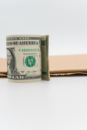 rolled up US dollar banknotes and brown paper on a white tabletop with text spaceの写真素材