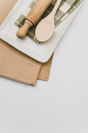 finely decorated stoneware dish and wooden kitchen tools on a brown paper and white backgroundの写真素材