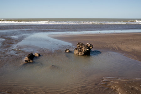 Pehuen-Co beach in Buenos Aires, Argentina. Rocks covered in mollusks. Sand and sea.の写真素材