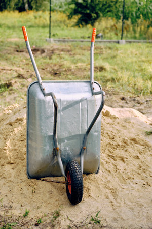 close-up of a metal wheelbarrow standing by a pile of sand