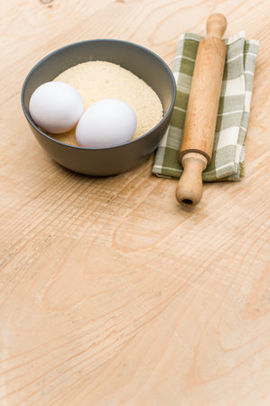 kitchen tools white eggs and dark gray bowl with wholegrain flour on worn wooden background with copy spaceの写真素材
