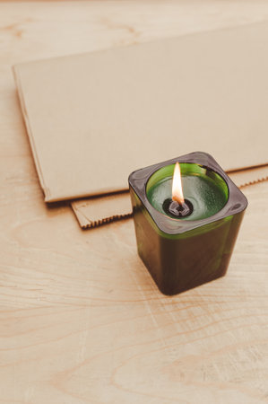 scented candle in a green glass burning on a rustic wooden tabletop with copy spaceの写真素材