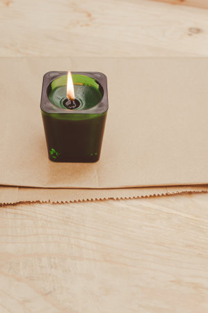 scented candle in a green glass burning on a rustic wooden tabletop with copy spaceの写真素材