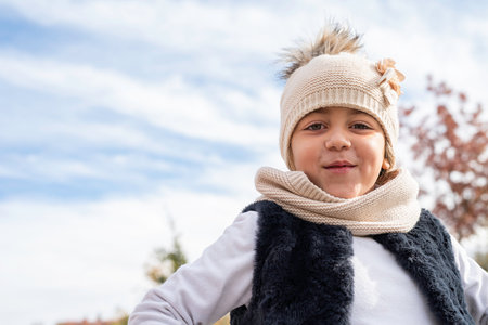 Close-up portrait of a happy Caucasian girl with a hat, gloves and scarf. Autumn concept. Copy space.の写真素材