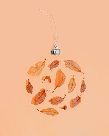 Vintage Christmas ball on nude pastel background. Christmas decoration is made of dry leaves with...
