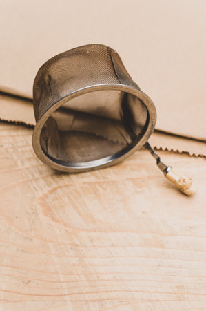 metal tea strainer on a kraft paper and wooden background with text spaceの写真素材