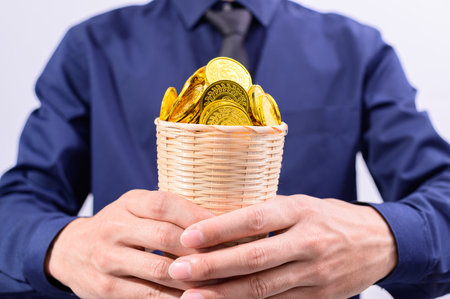 Hand holding a basket full of moneyの写真素材