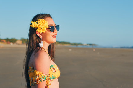 A portrait of a woman in a yellow summer outfit at the beachの写真素材