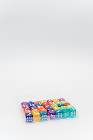 plastic box with colorful dice on a white tabletop with copy spaceの写真素材