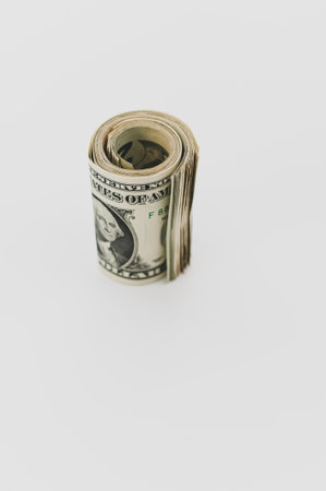 US dollar banknotes rolled up on a white tabletop with text spaceの写真素材