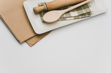 finely decorated stoneware dish and wooden kitchen tools on a brown paper and white backgroundの写真素材