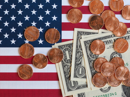 One Dollar banknotes and One Cent coins (USD) currency money over the flag of the United States