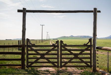 gate overlooking rural landscape with mountains and pastureの写真素材