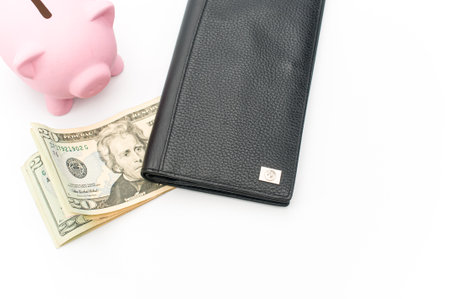a cute pink piggy bank with wallet and a banknotes wad on a white tabletop with copy space
