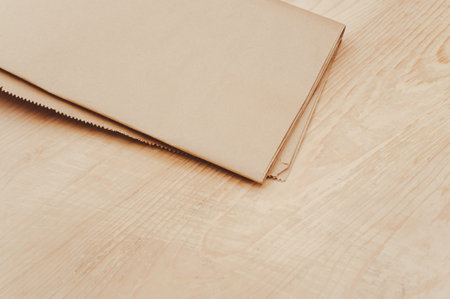 folded kraft paper bag on a rustic wooden tabletop with copy spaceの写真素材