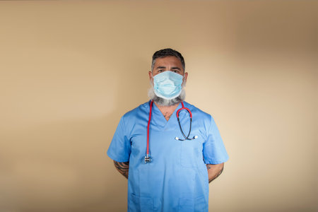 portrait of a male nurse in blue gown and mask on a light backgroundの写真素材