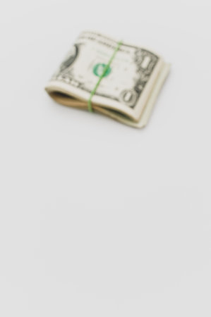 US dollar banknotes wad on a white tabletop with text space