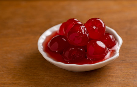 maraschino cherries in a small porcelain bowl on a wooden baseの写真素材