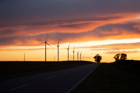 sunrise on a road with wind power generating mills