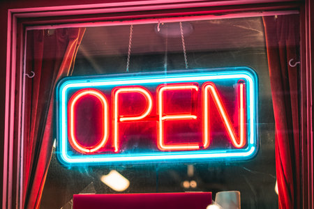 A bright, neon open sign hanging in a shop window.の写真素材