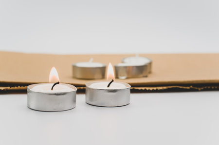 row of white scented wax tea lights on a white tabletop with copy space and folded paper bagの写真素材