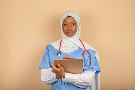 Young woman of Muslim religion holding clipboard and writing something close up. Medical care, insurance, prescription.の写真素材