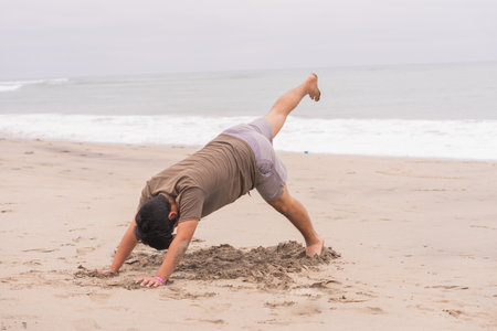 Young man practicing various poses in yoga on the beach. Enjoying a great day and sun.の写真素材