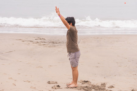 Young man practicing various poses in yoga on the beach. Enjoying a great day and sun.の写真素材