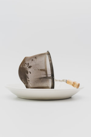 a white plate with tea metal filter and tea leaves inside on a white backgroundの写真素材