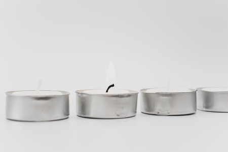 row of white scented wax tea lights on a white tabletop with copy spaceの写真素材