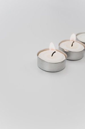row of white scented wax tea lights on a white tabletop with copy spaceの写真素材
