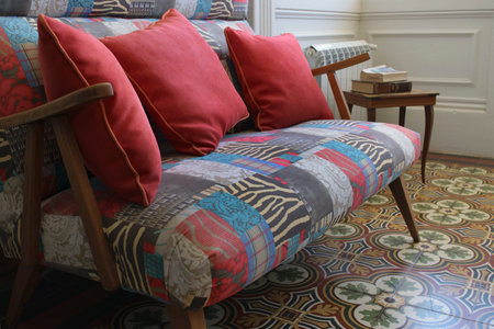 Antique armchair decorated with red cushions and multicolored upholstery on an antique floor of the...