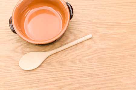 spoon and rustic terracotta bowl on a wooden background with text spaceの写真素材