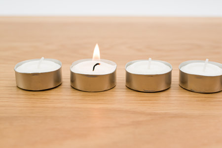 row of white scented wax tea lights on a wooden tabletop with copy spaceの写真素材
