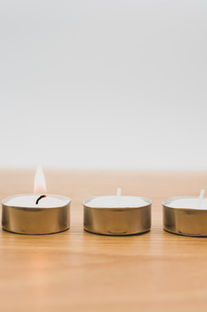 row of white scented wax tea lights on a wooden tabletop with copy spaceの写真素材