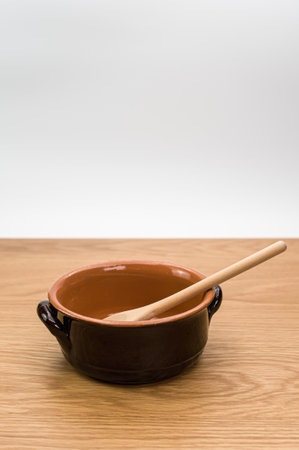 spoon and rustic terracotta bowl on a wooden background with text spaceの写真素材