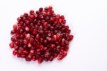 Pile of fresh pomegranate seeds isolated on white. Red healthy fruit. Top view. Food and healthy lifestyle concept. Copy space.の写真素材