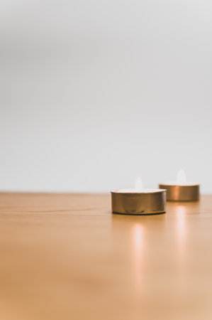 row of white scented wax tea lights on a wooden tabletop with copy spaceの写真素材