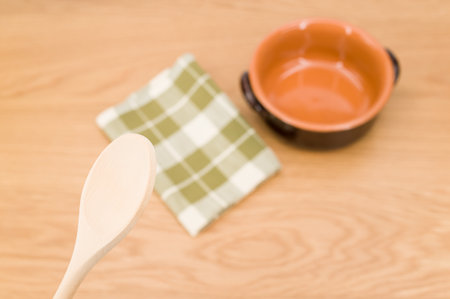 natural terracotta bowl and wood kitchen utensils and a table napkin on a wooden background with copy spaceの写真素材