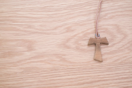 natural wood tau cross with lace on a wooden background with copy spaceの写真素材