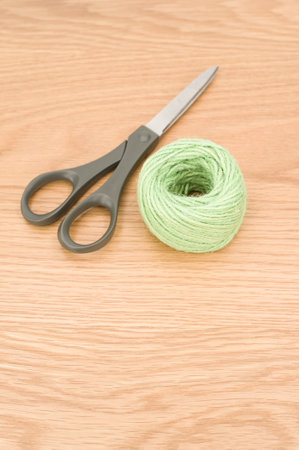 scissors and rough cotton decorative yarn on a wooden background with text spaceの写真素材
