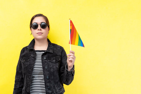 Serious young woman hold lgbtq+ pride flag. Queer concept.の写真素材