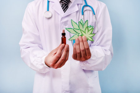 Doctor hands holding cardboard figure of cannabis leaves. Marijuana symbol medical concept.の写真素材